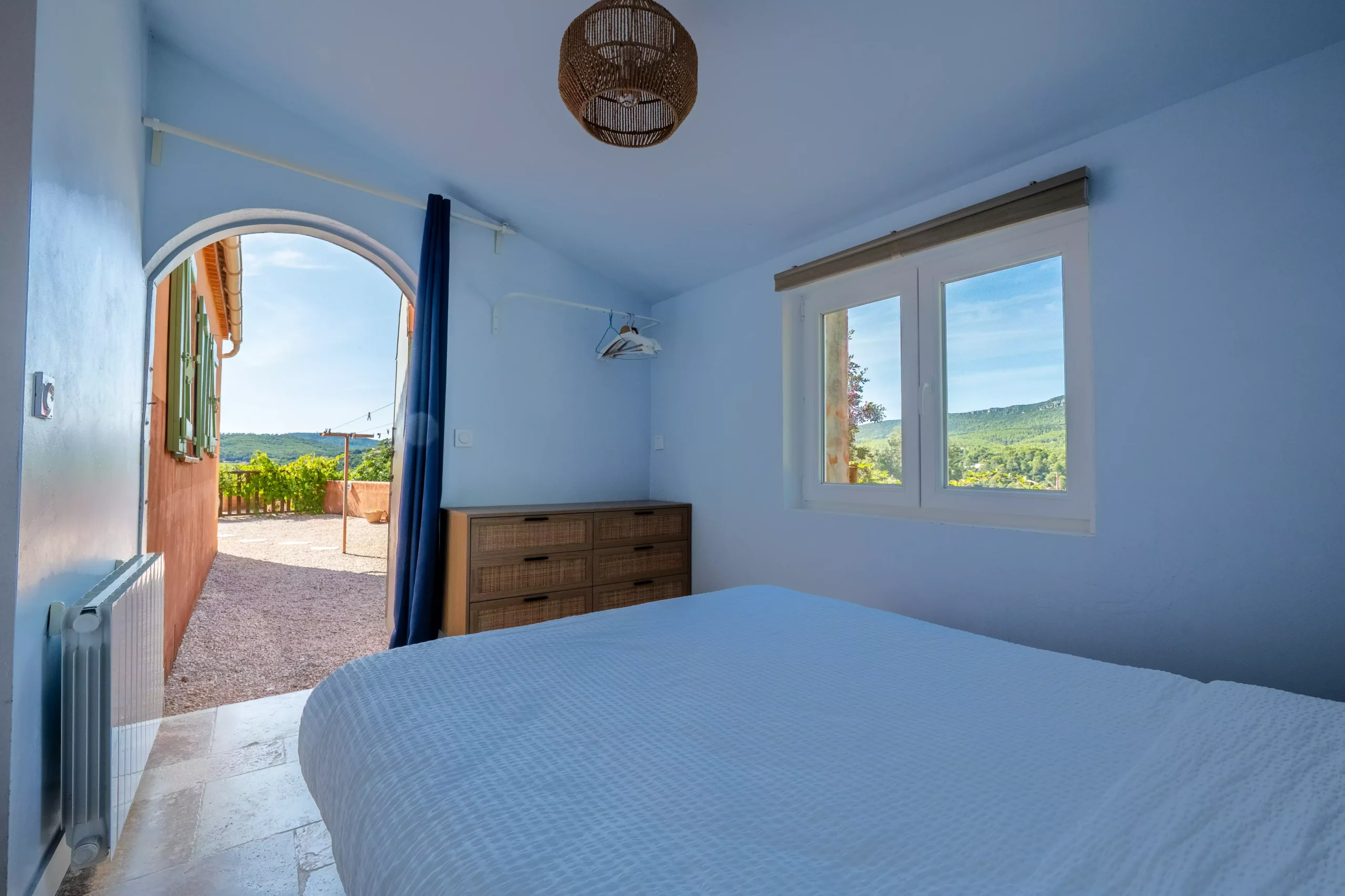 Villa Le Perchoir - Chambre avec vue sur les collines et porte en arche typique de la Provence.